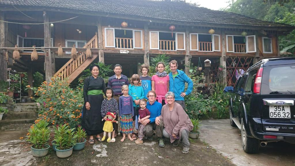 A local family and travelers share a meal during the Ha Giang Jeep Tour for Couples and Families in a traditional wooden house. 