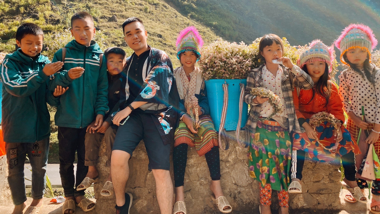Traveler sharing stories with local Hmong guide beside Jeep in Ha Giang mountains.